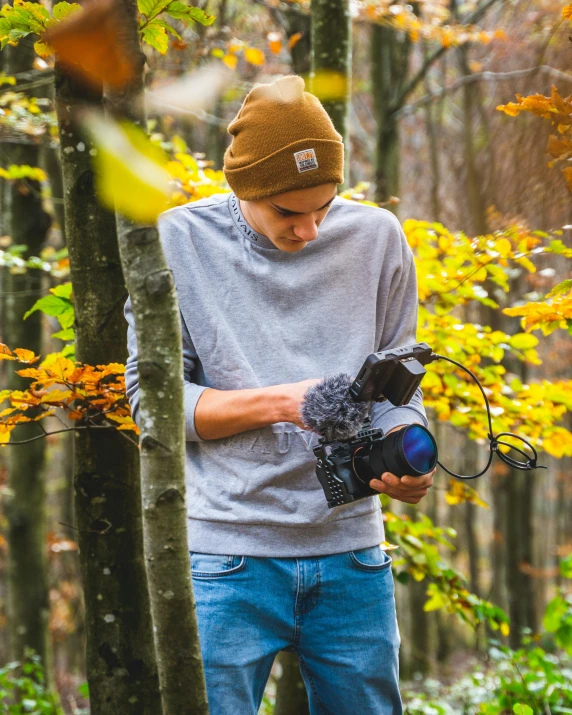 a man standing in the woods, holding a camera and a hand