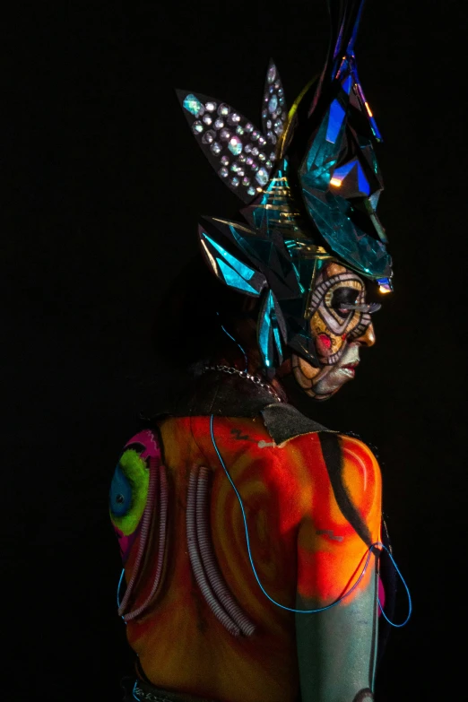 a woman with dark makeup and black dress has a colorful headpiece