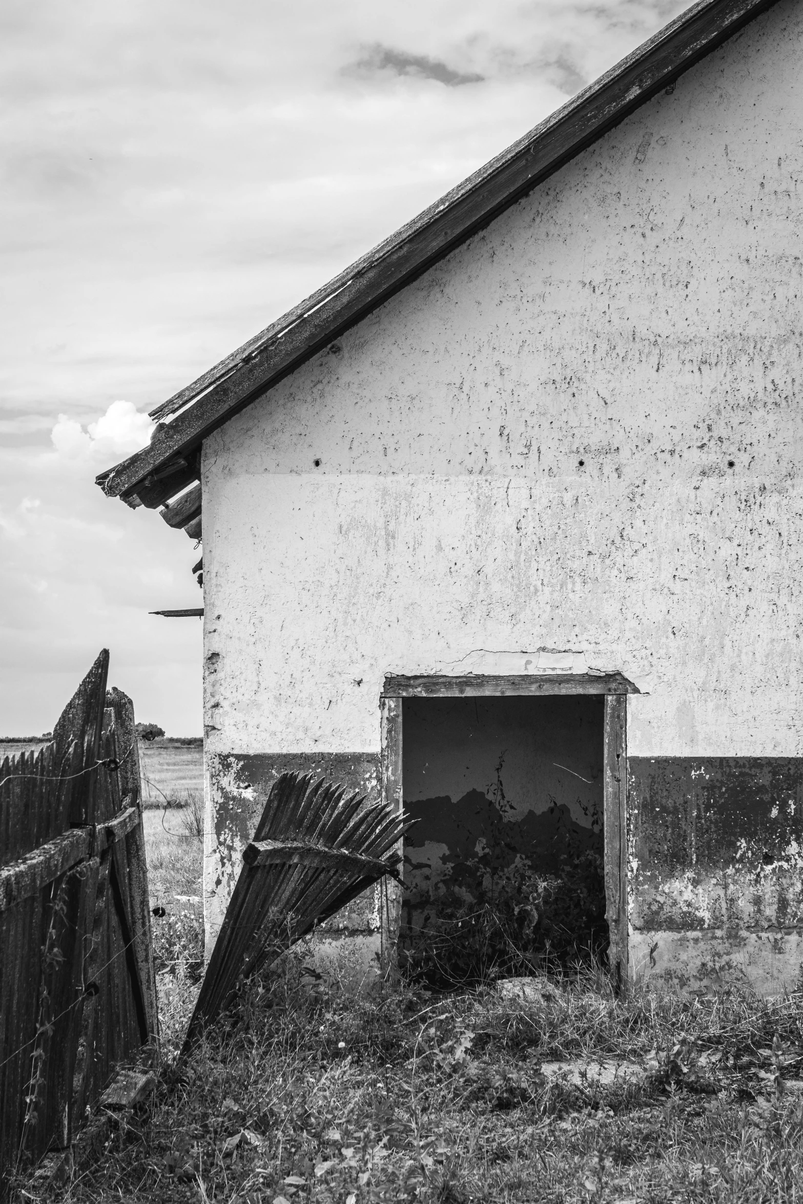 an old building with a broken window next to a wooden fence