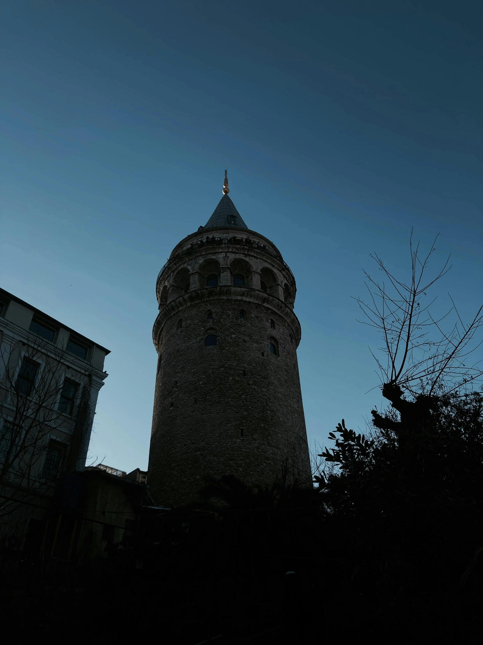 a dark tower that is standing next to some buildings