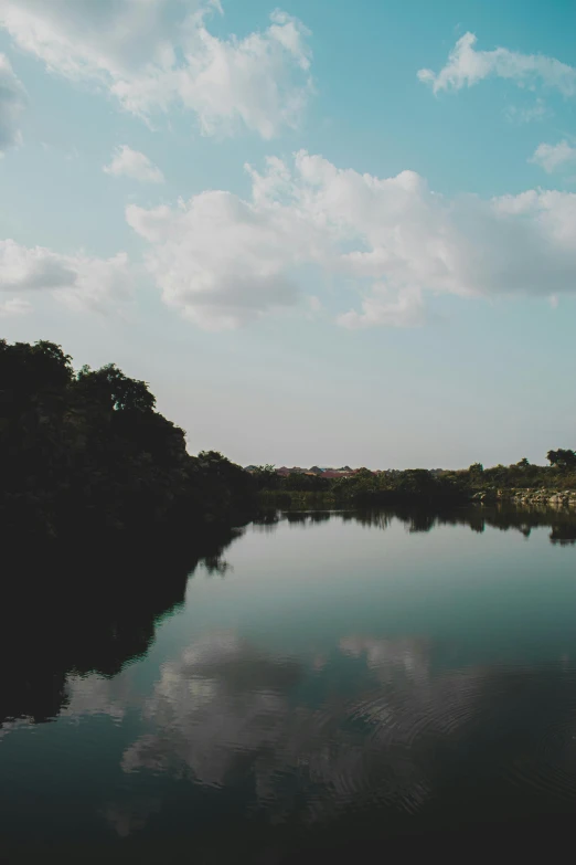 a body of water surrounded by forest under cloudy skies