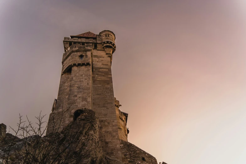 a very tall brick tower against a pink sky