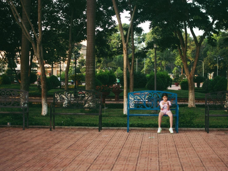 a woman in a pink shirt sitting on a blue bench