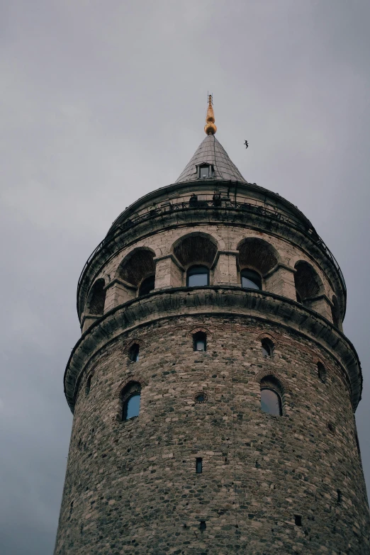 a grey stone tower on top of a cloudy blue sky