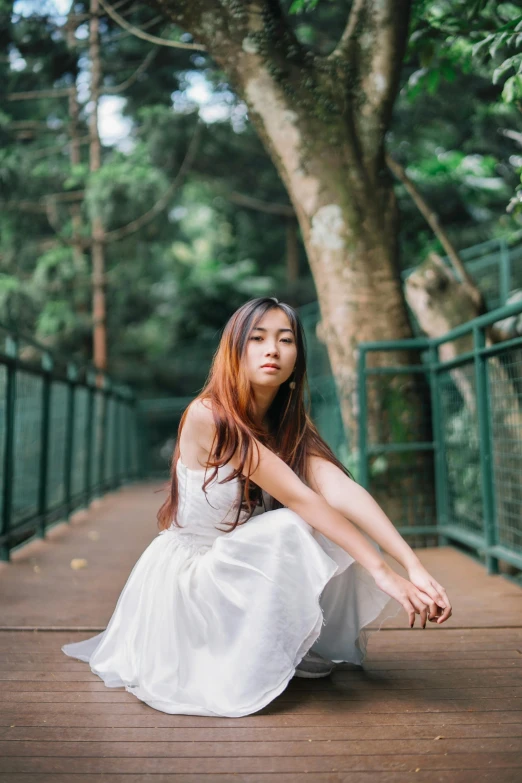 young lady sitting on walkway in dress posing for pograph