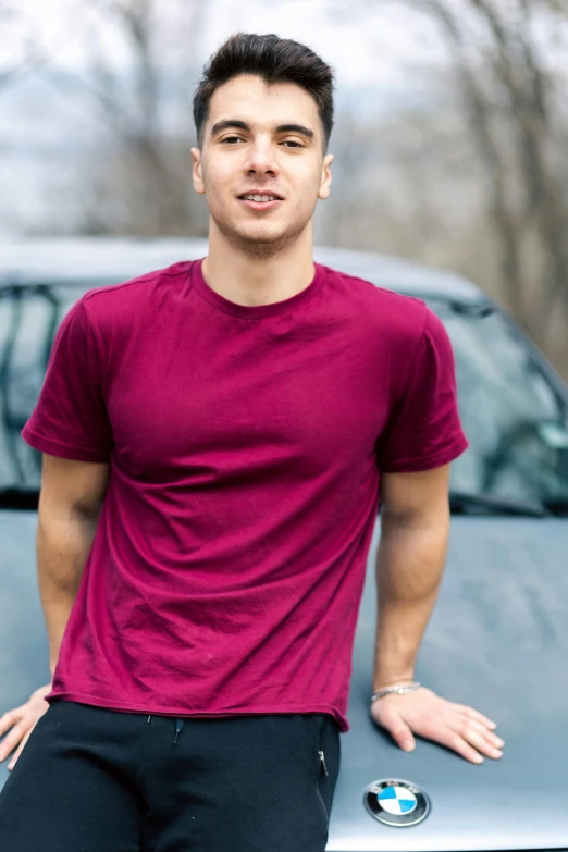 a man is standing with his arms crossed in front of a car
