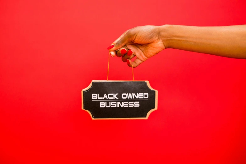 black owned business sign being suspended by woman's hand