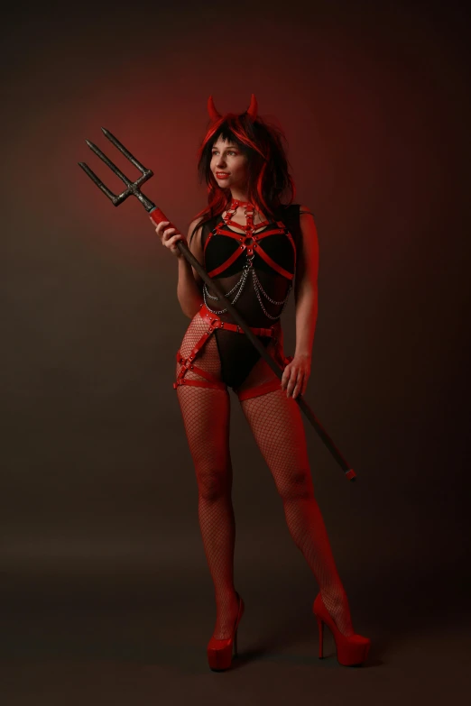 woman dressed as devil holding two large black forks