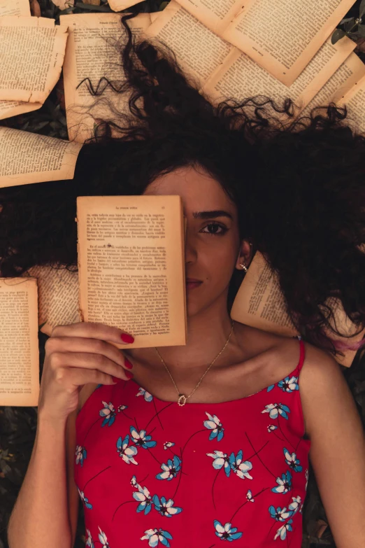 a woman with a red top laying on a floor with books