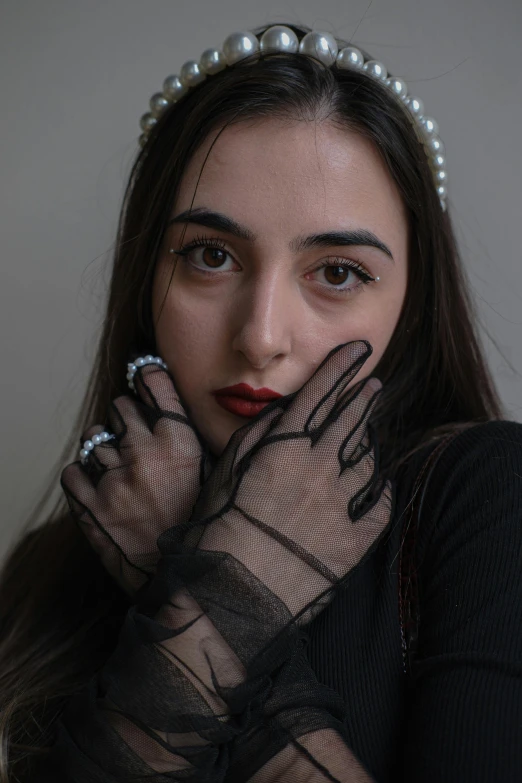 a woman in a mesh and pearls dress is putting her hands up to her face