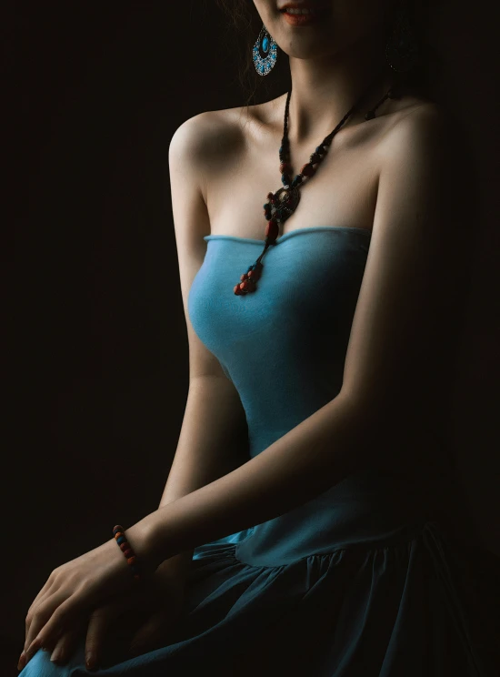 a woman in a blue dress wearing necklace and earrings