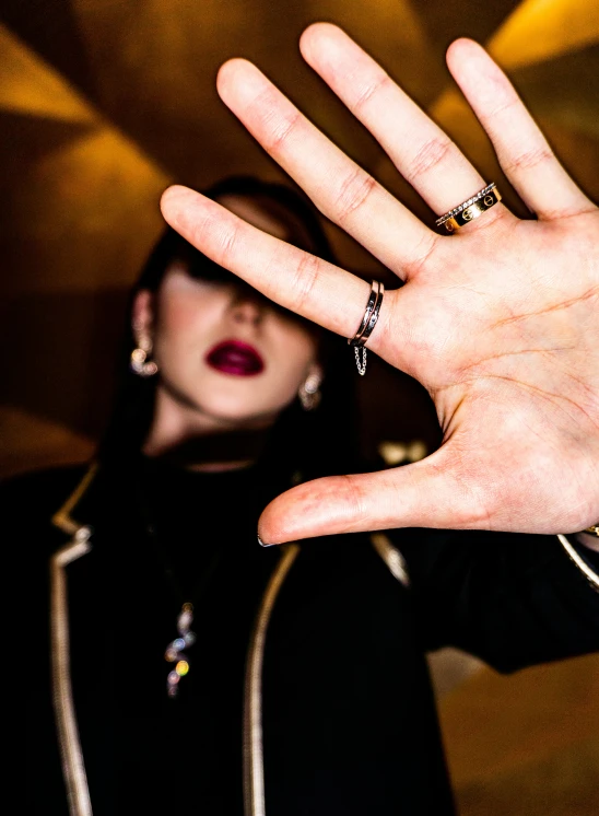 woman posing in front of a picture and showing a hand with a wedding band on it