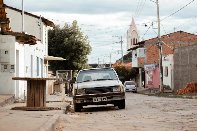 a dirty car parked on a street in front of a house