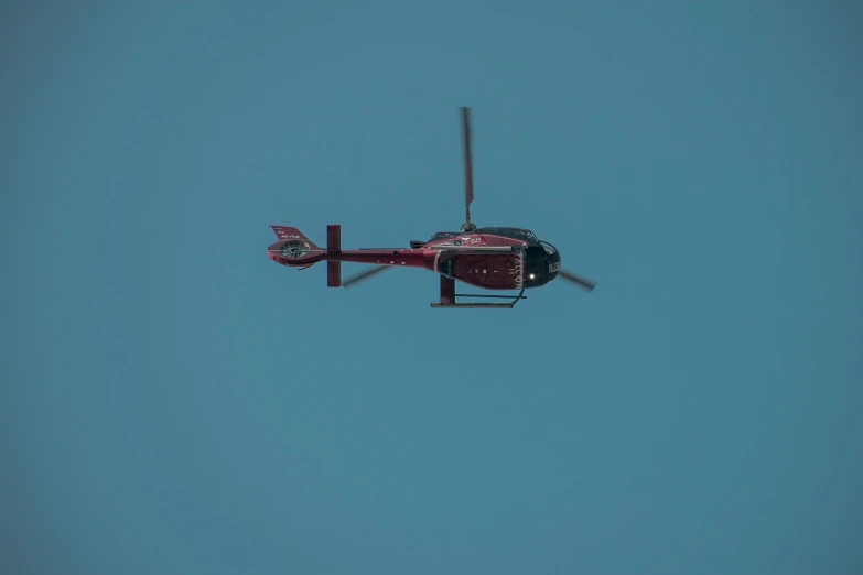 a helicopter flying against a blue sky that has no clouds