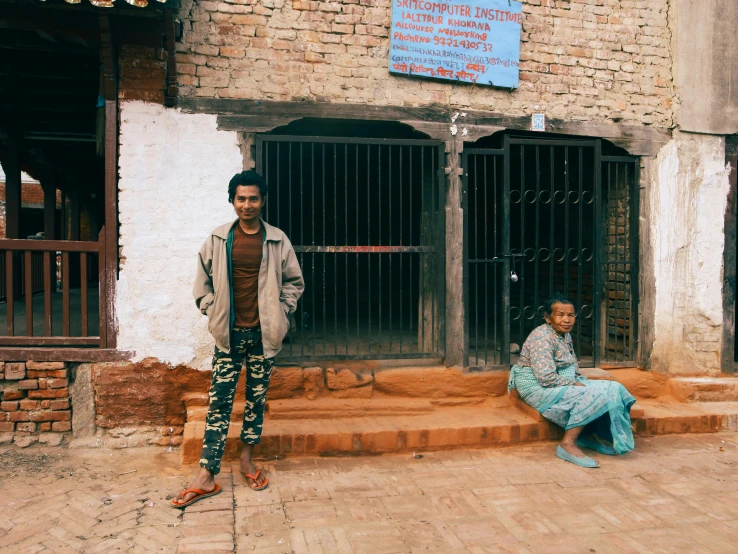 two men standing next to each other on a brick sidewalk