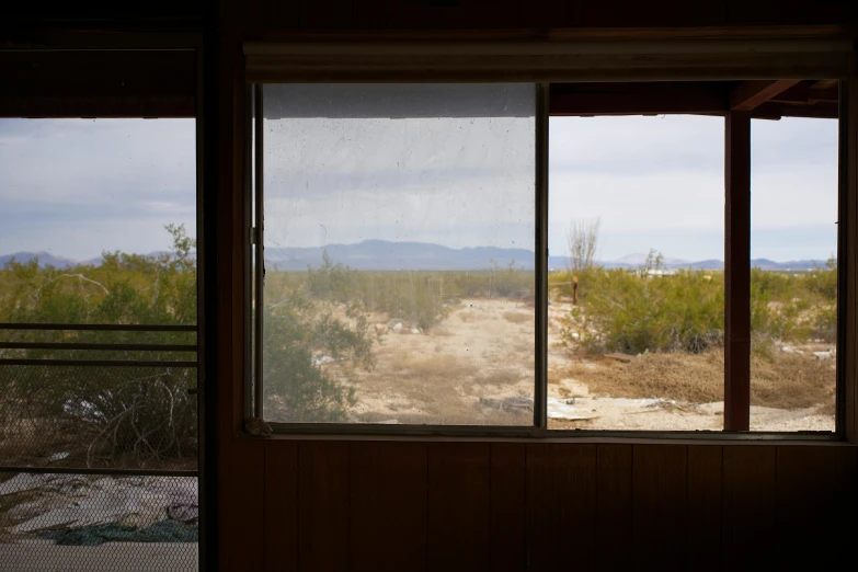 a room with a window and view of dirt field outside