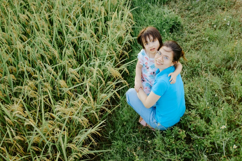 two little girls are sitting together in the tall grass