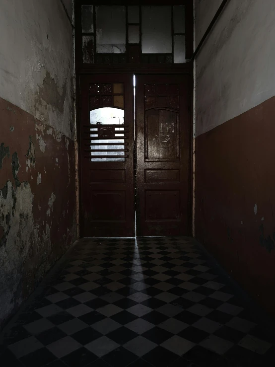 a large wooden door with one side opened and a checkerboard floor