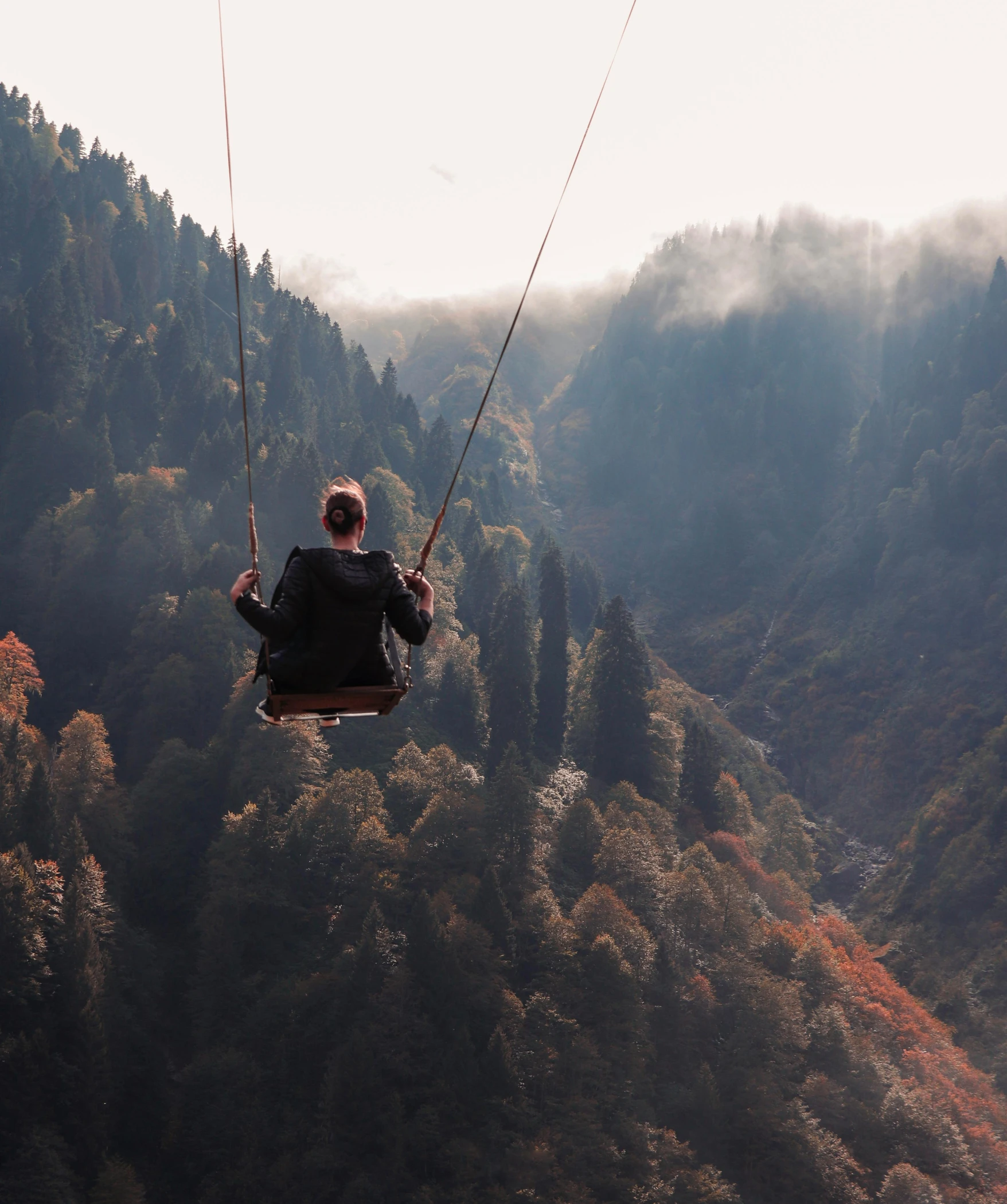 a man on a zip line over a mountain with trees