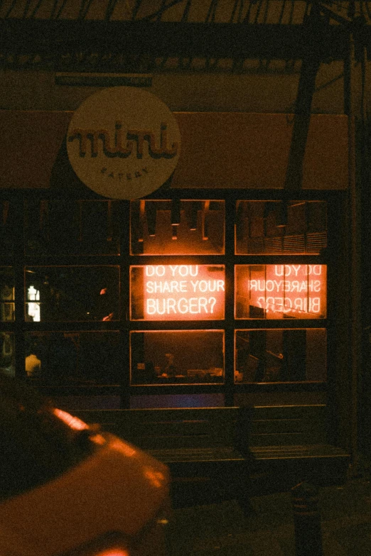 a storefront is lit up at night with neon signs