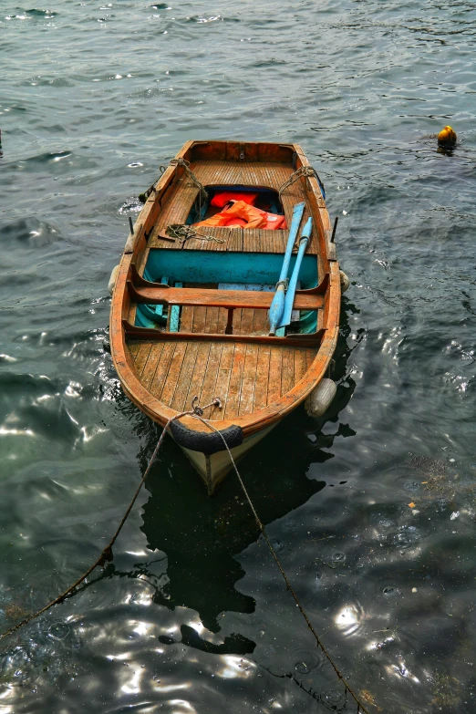a wooden boat with the paddles out in the water