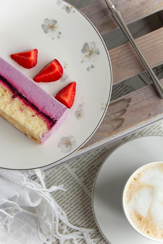 a white plate topped with a piece of cake and fresh strawberries