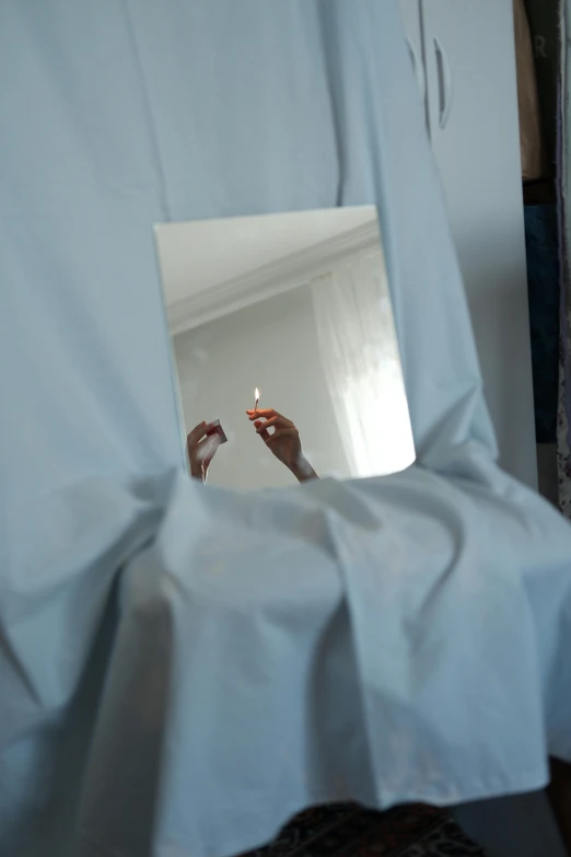 a person is taking a picture with their phone through a piece of white cloth