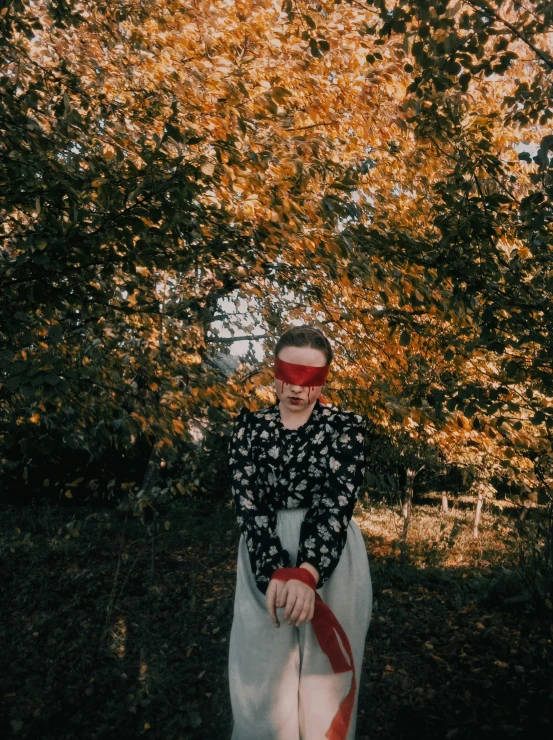 a woman wearing a blindfold riding a horse under trees