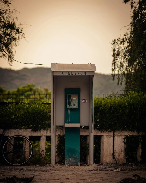 a vintage phone booth sitting next to a bike parked outside