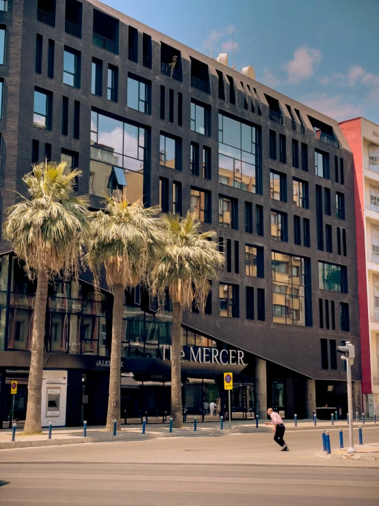 a woman is walking past a tall black building