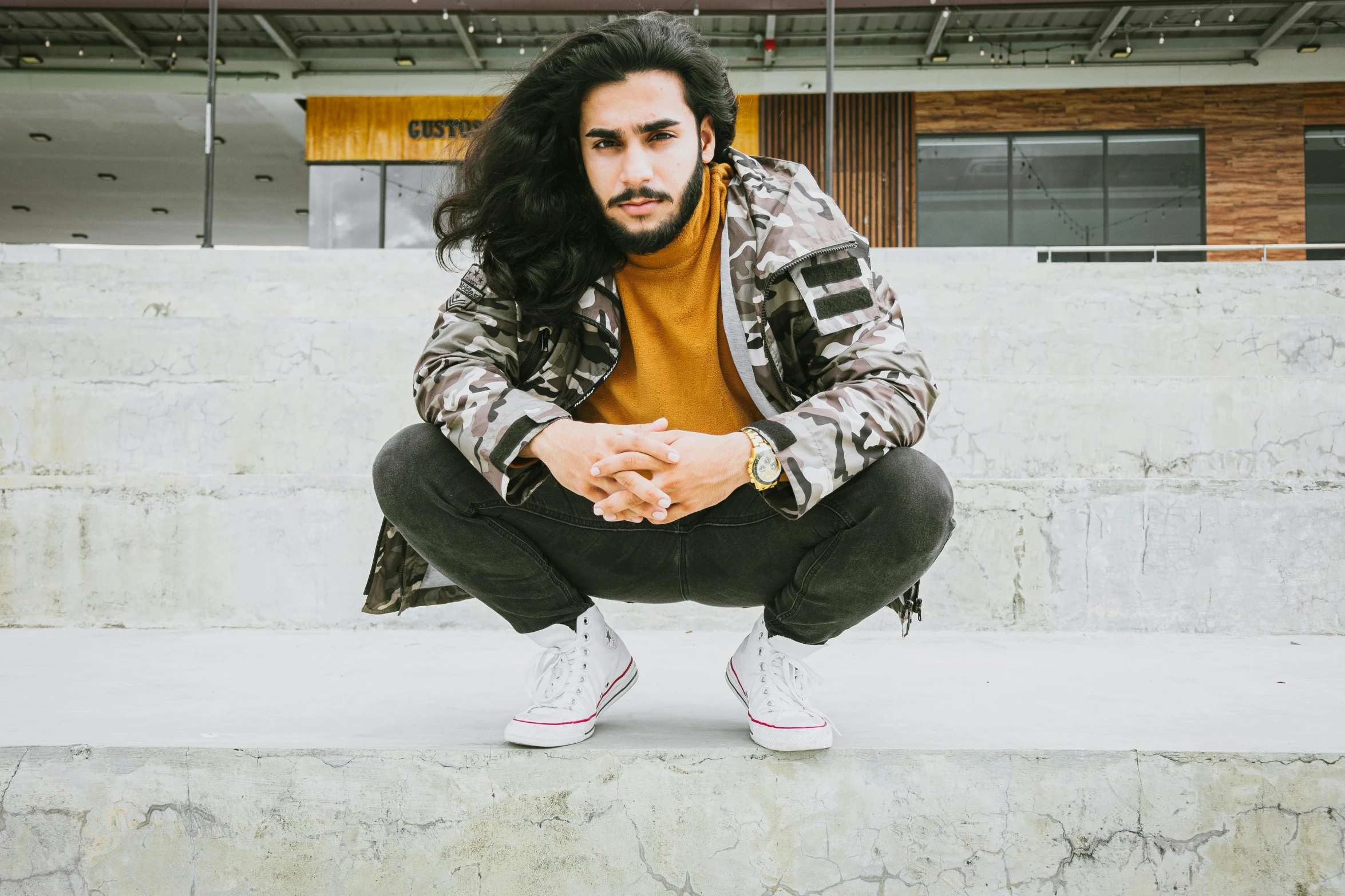 a man posing with a skateboard outdoors