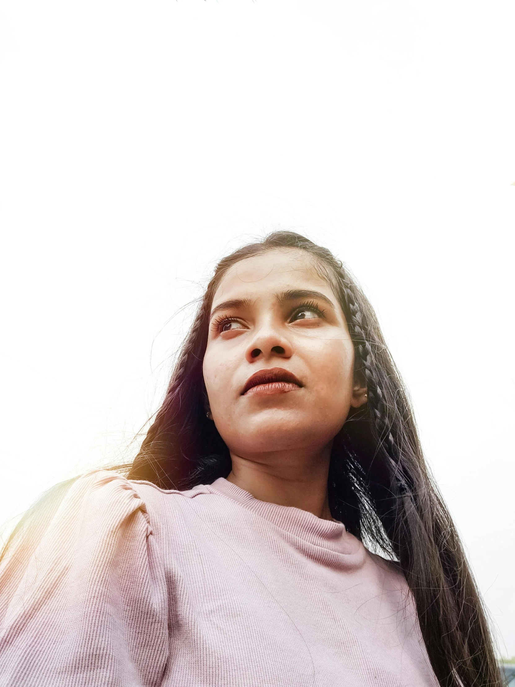 a girl stands looking off to the side in an open field