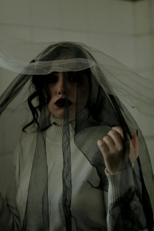 a woman standing behind veil with finger through her mouth
