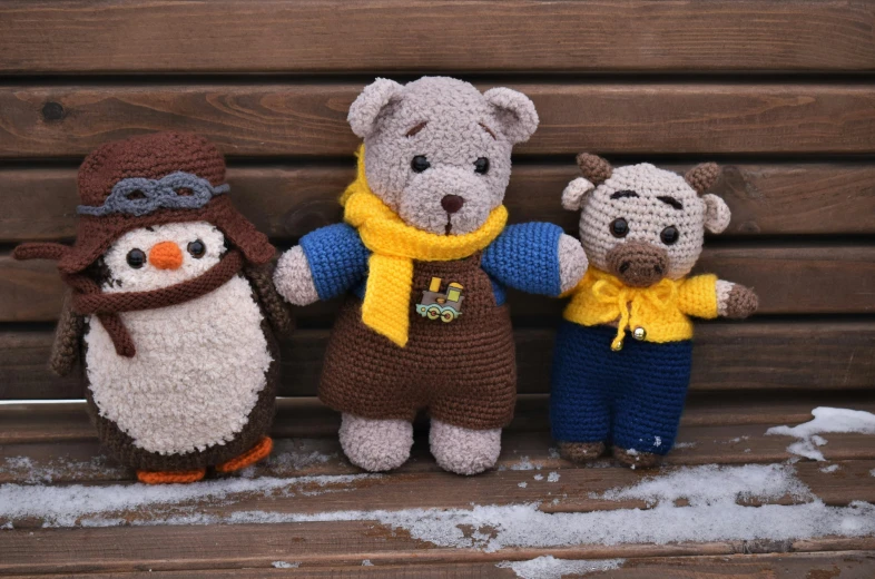 three stuffed animals dressed in various crochet clothing