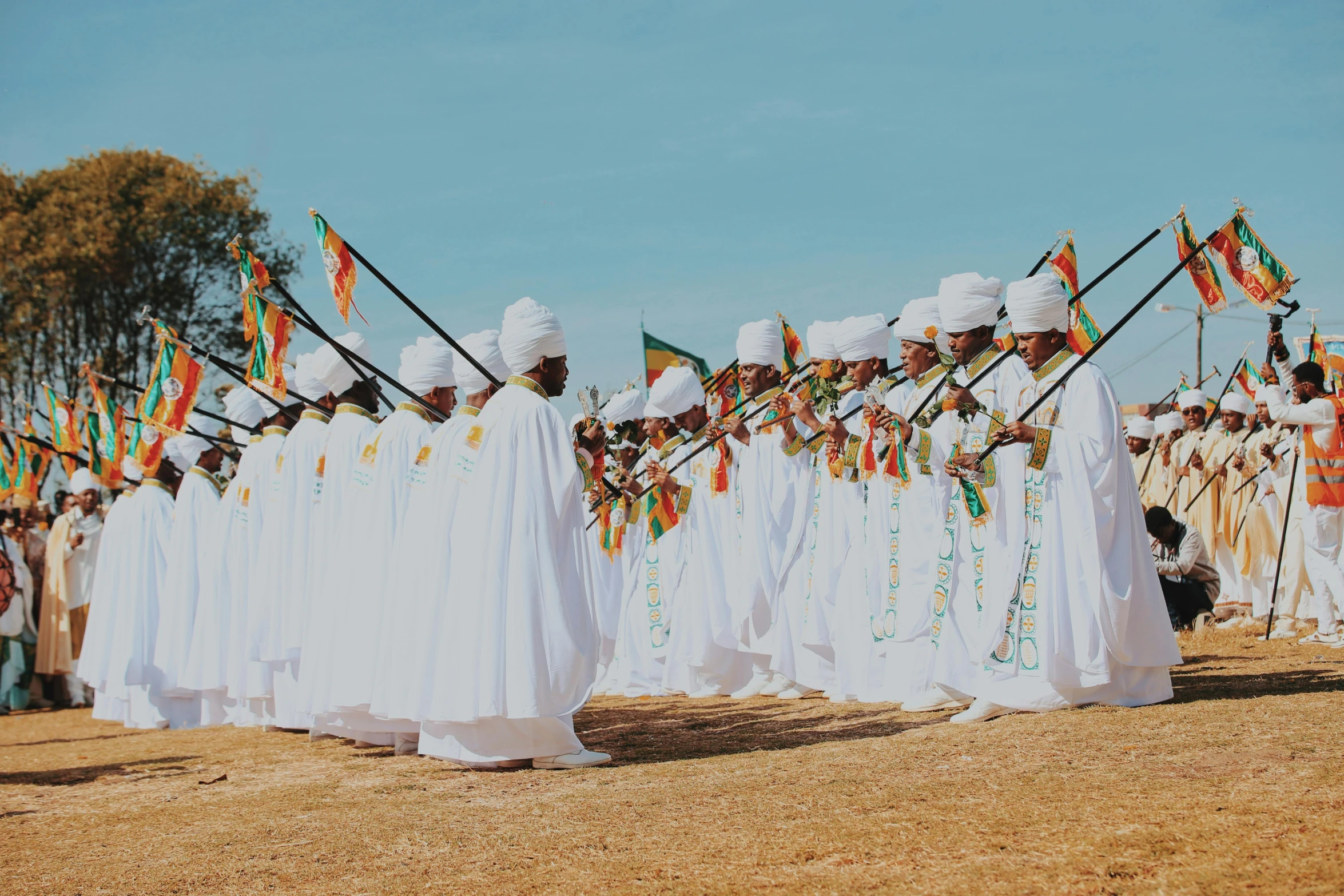 people dressed up with ceremonial clothing holding flags in the sand