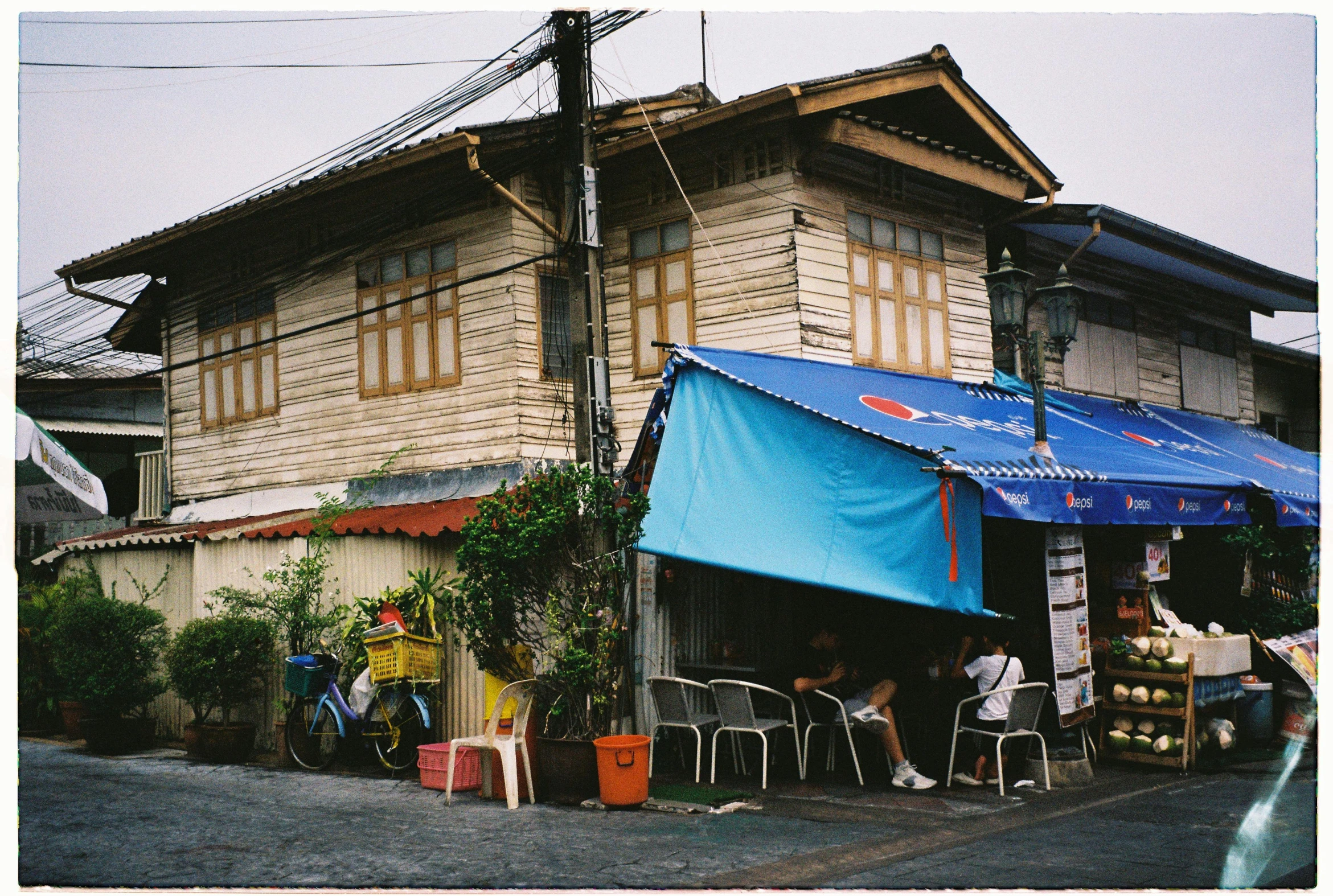 a street side shop with chairs and people shopping