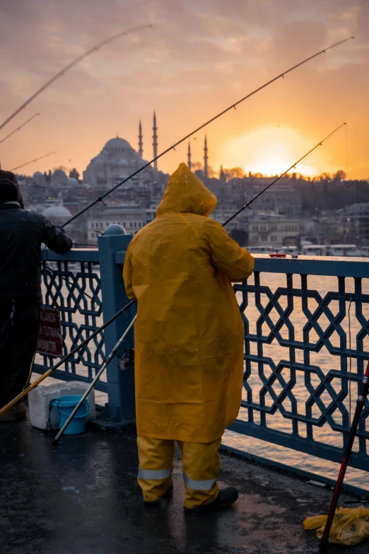 a couple of people on a bridge fishing at sunset