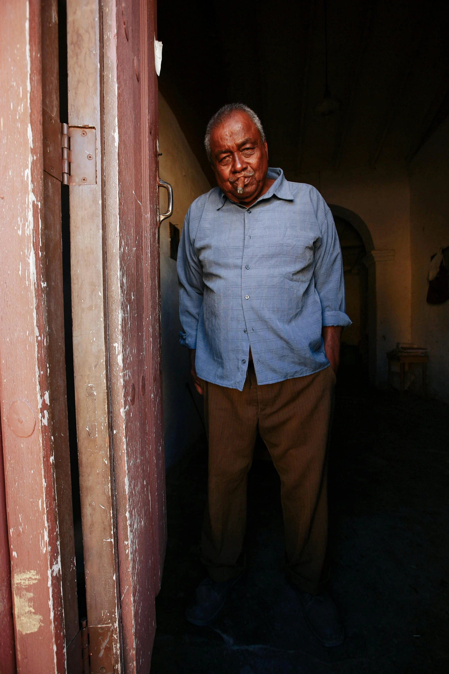 a older man standing in the doorway to his house