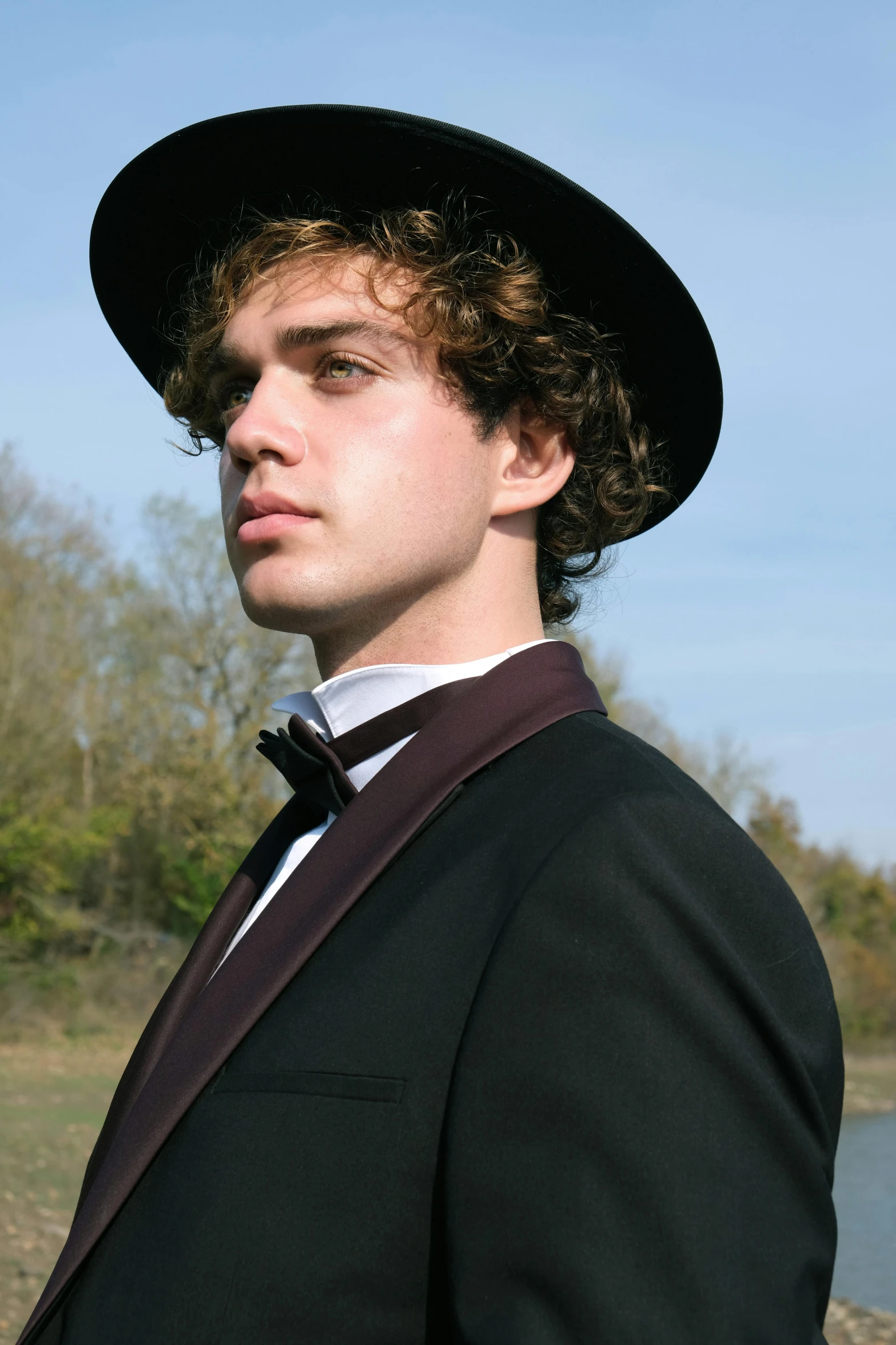 a young man in a hat and coat with a bow tie