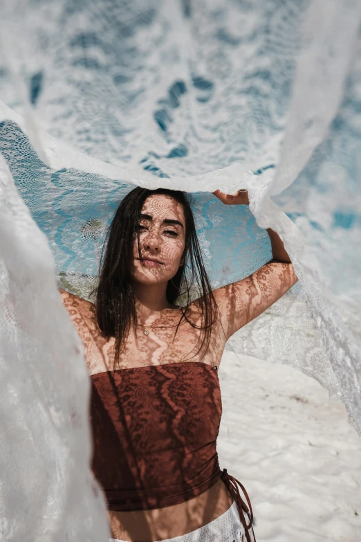 a woman with wet hair holds up a surfboard over her head