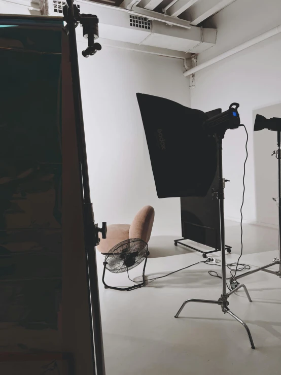 a pograph studio with a tripod and chairs and lighting equipment