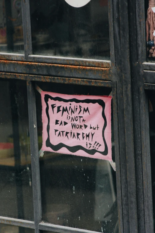 pink sign posted on a black metal frame in a window