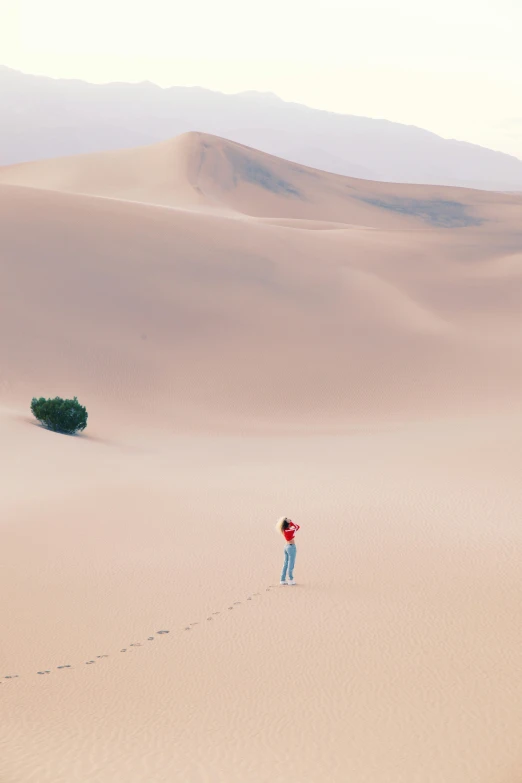 a man walking across a sandy field holding onto his surfboard