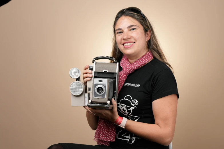 a girl sitting on a chair holding up an old - style camera