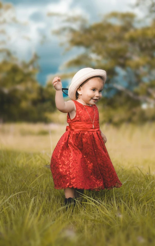 a girl stands in the grass holding a kite