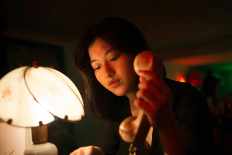 a woman in the dark looking at a table lamp