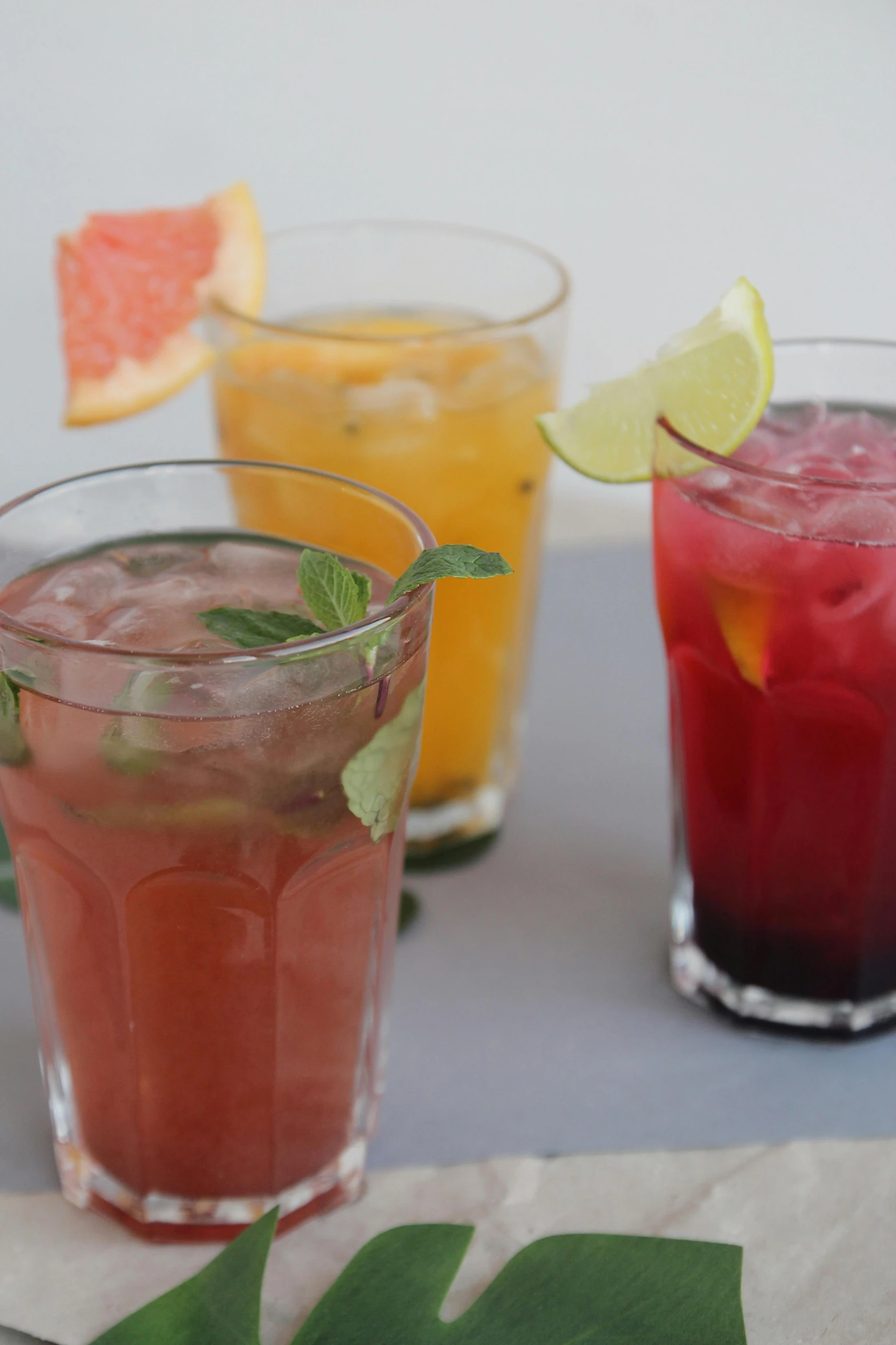 three colorful beverages are sitting on a table