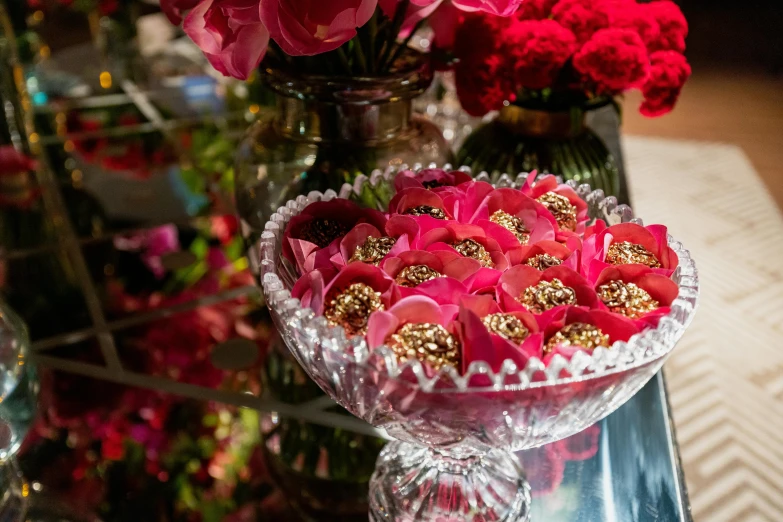 a table full of glass vases filled with red flowers