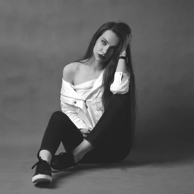 black and white pograph of a woman sitting down with her long hair blowing in the wind