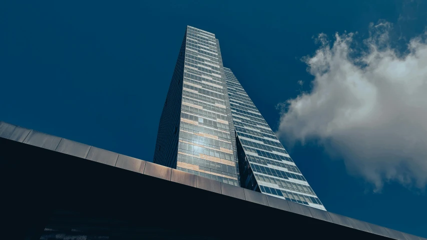 looking up at a tall skyscr with a few clouds in the background